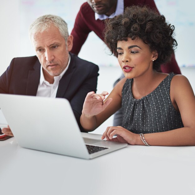 Photo being techsavvy is an essential element of managing your business cropped shot of a group of businesspeople discussing something on a laptop