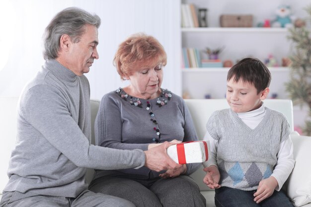 Bejaard echtpaar geeft een cadeau aan hun kleinzoon op zijn verjaardag