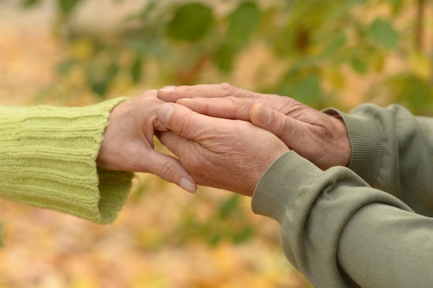 Bejaard echtpaar hand in hand in herfstpark