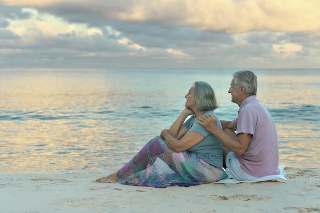 Bejaard echtpaar zittend op de kust en kijkt naar de zee