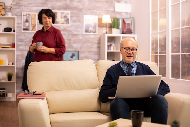 Bejaard oud echtpaar dat moderne laptop gebruikt om met hun kleinzoon te chatten. Grootmoeder en grootvader met behulp van moderne technologie