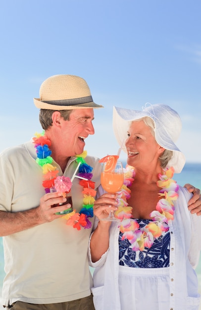 Bejaard paar dat een cocktail op het strand drinkt