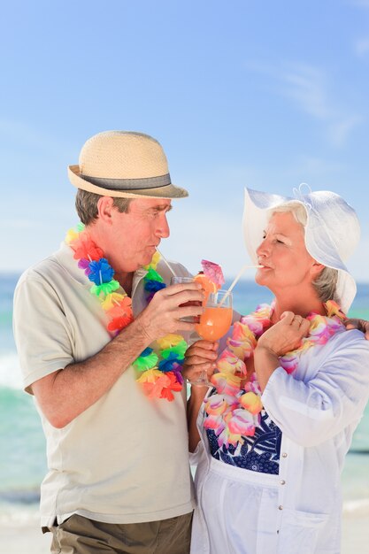 Bejaard paar dat een cocktail op het strand drinkt