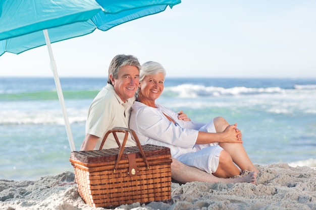 Bejaard paar die op het strand picknicken