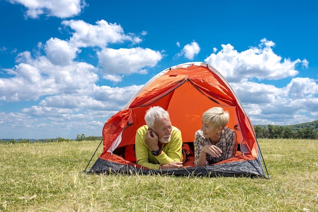 Bejaard wandelpaar in een tent na een wandeling op een weiland