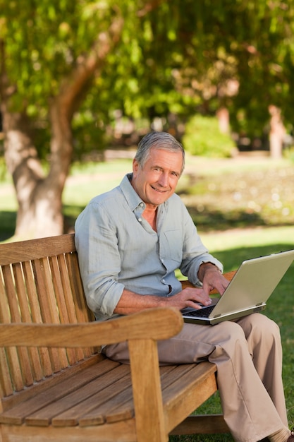 Bejaarde die aan zijn laptop in het park werkt