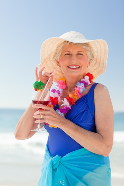 Bejaarde die een cocktail op het strand drinkt