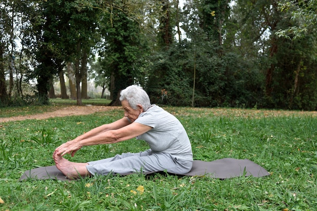 Bejaarde die yoga in openlucht praktizeert