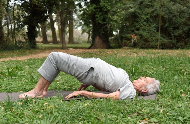 Bejaarde die yoga in openlucht praktizeert