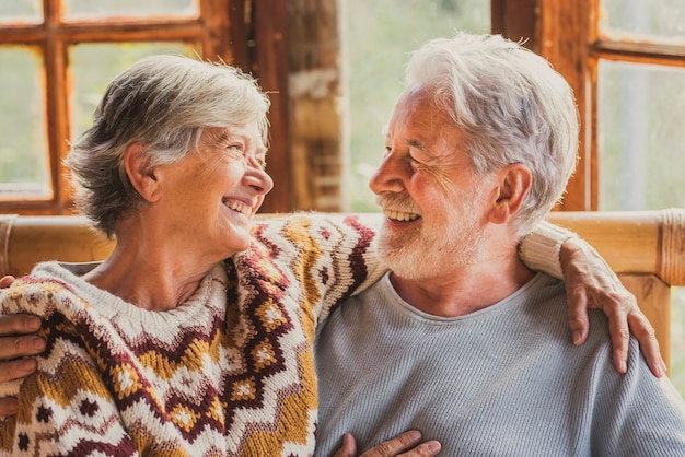 Bejaarde echtpaar gelukkige levensstijl met man en vrouw die elkaar aankijken met liefde en vriendschap om thuis te zitten. Vrolijke mensen op oudere leeftijd genieten van het leven en vrijetijdsbesteding binnenshuis
