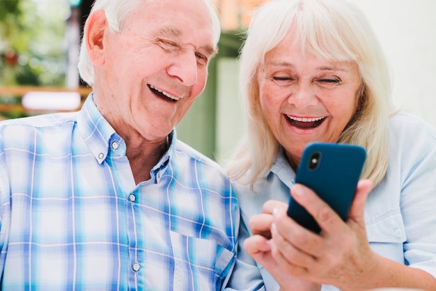 Bejaarde en vrouw die smartphone het glimlachen gebruiken