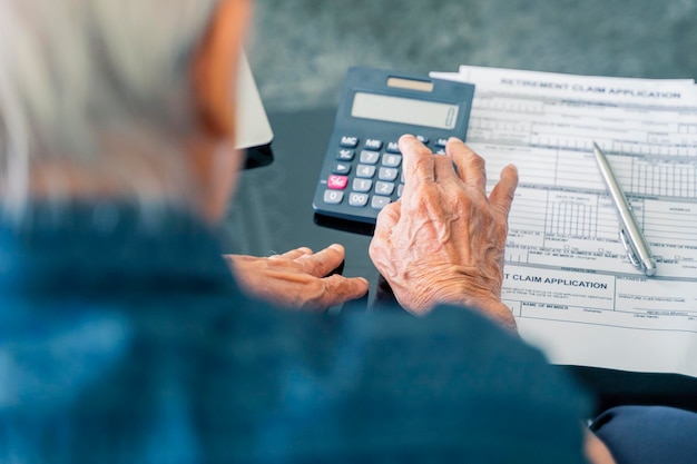 Bejaarde man die besparingen berekent in de buurt van pensioenformulier