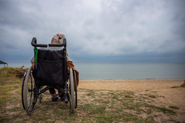 Bejaarde oma zit in een rolstoel aan zee