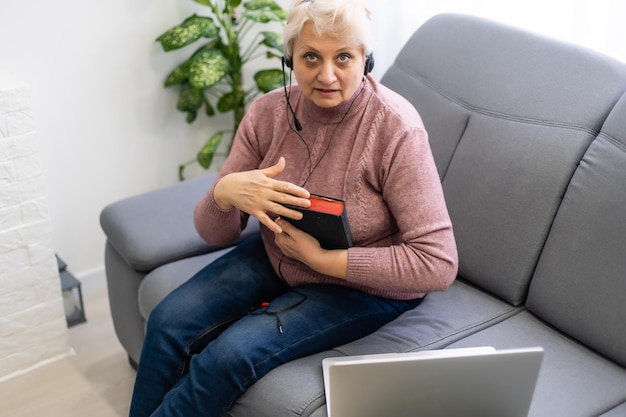 bejaarde vrouw met bijbel en laptop voor haar verbonden met online kerkdiensten tijdens de uitbraak van covid 19