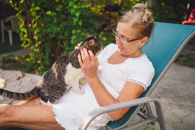 Bejaarde vrouw ontspannen in de tuin met een kat