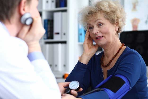 Bejaarde vrouw zit op doktersbezoek en klagen over hoofdpijn