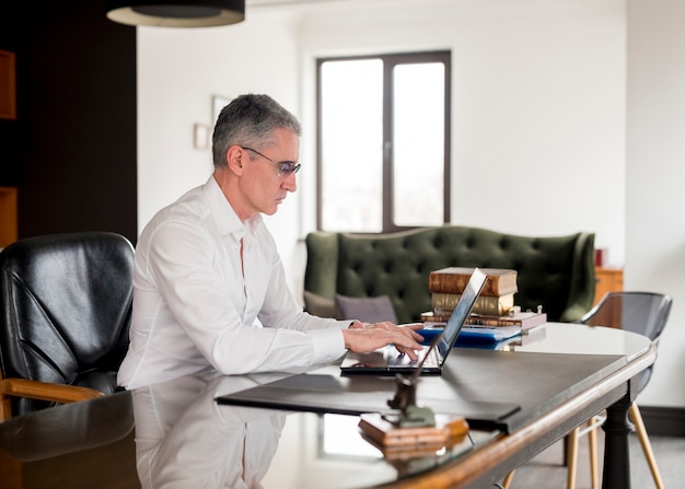 Foto bejaarde zakenman die zijn laptop met behulp van