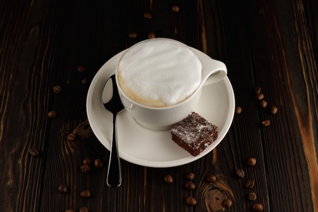 Beker cappuccino op een donkere houten achtergrond met koffiebonen