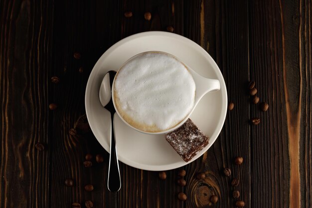 Beker cappuccino op een donkere houten achtergrond met koffiebonen