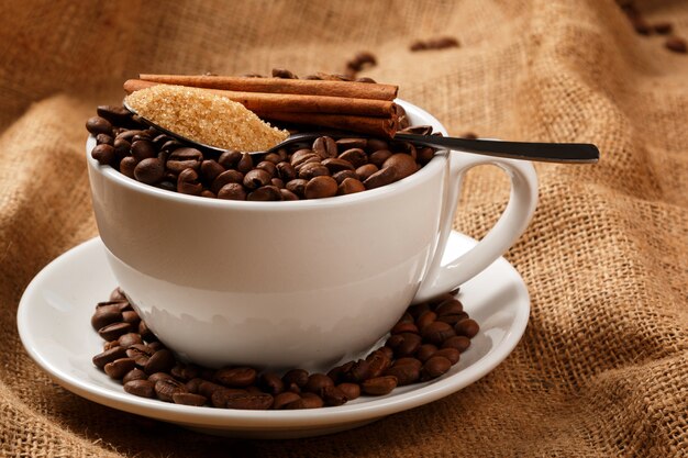 Beker gevuld met koffiebonen en lepel met bruine suiker