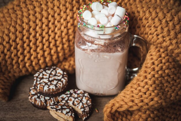 Beker met cacao en marshmallows, chocoladeschilferkoekjes en gele sjaal