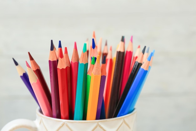 Beker met kleurrijke potloden op onscherpe achtergrond