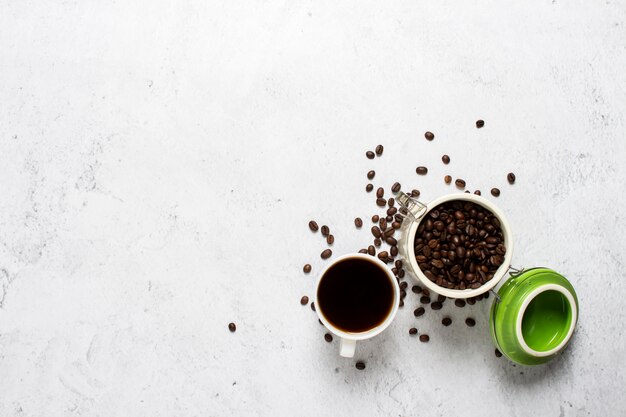 Beker met koffie, een blikje koffiebonen en koffiebonen zijn verspreid op een concrete achtergrond.