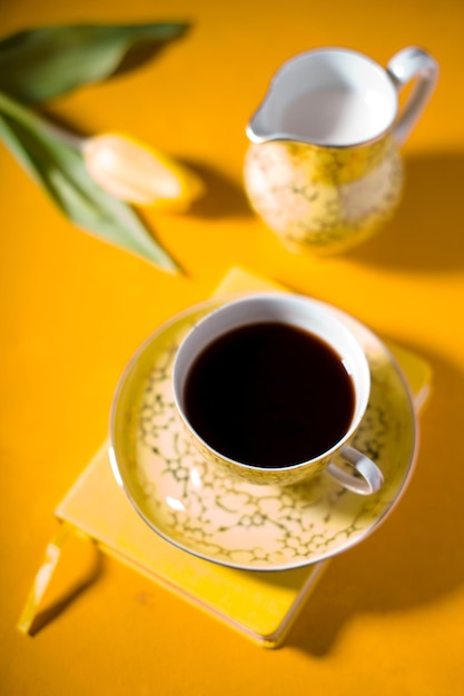 Beker met koffie notebook tulp op gele achtergrond