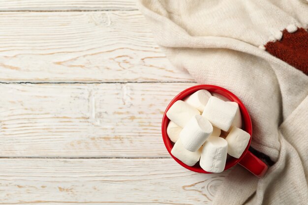 Beker met marshmallows en trui op houten achtergrond