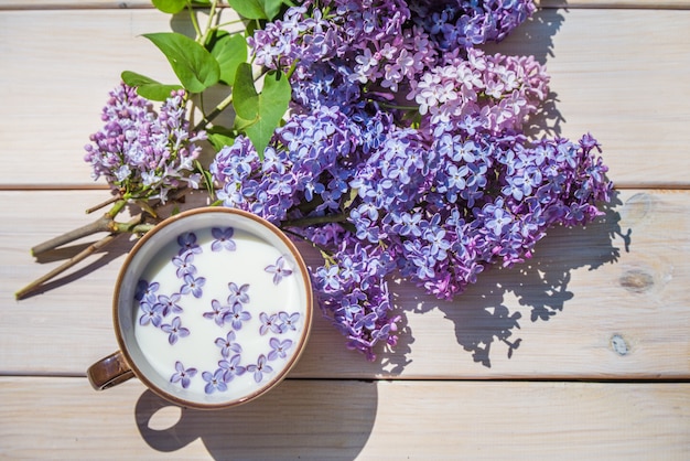 Beker met melk en kleine paarse lila bloemen