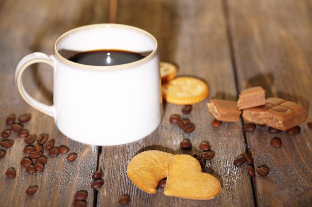 Beker met warme koffie en zoete koekjes op houten tafel achtergrond