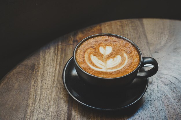 Foto beker op houten bureau van bovenaf als ontbijt in een koffieshop tijdens het werk