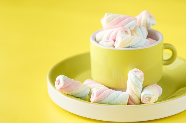 beker vol zoete gedraaide marshmallow op heldere gele achtergrond