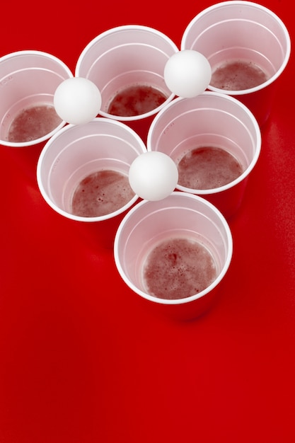 Bekers en plastic bal op rode achtergrond. Beer pong spel