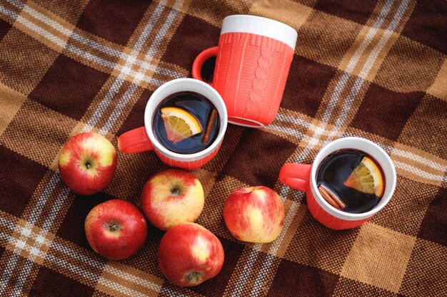 Bekers met glühwein en rode appels op een deken