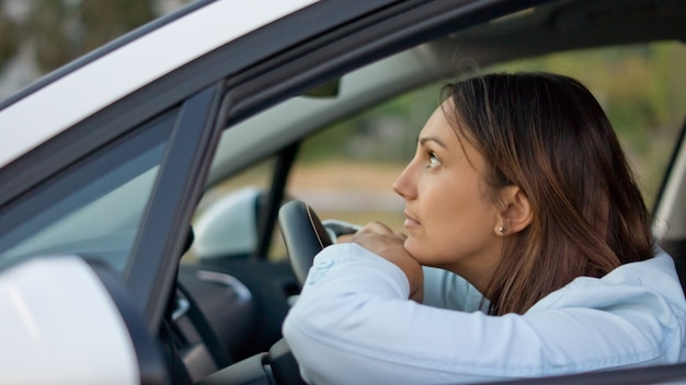 Bekijk door het open raam van een aantrekkelijke vrouw die geduldig in haar auto wacht