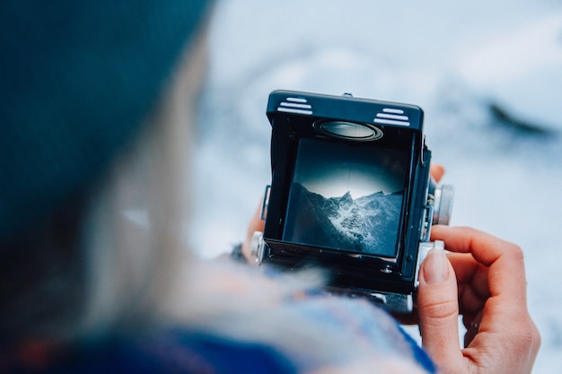 Bekijk het berglandschap door de zoeker van de oude camerafoto. Fotograaf van de oude school neemt het op tegen een retro filmcamera.