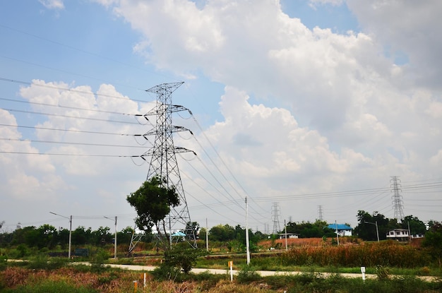 Bekijk landschapsplatteland met hoogspanningsmastpaalkolom voor lokale elektrische voeding stalen paalsteun bovengrondse hoogspanningslijnen op pad van landelijke dorpsvallei in Bangkok, Thailand