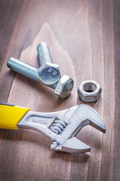 Bekijk op moersleutel en bouten op vintage houten plank bouwconcept