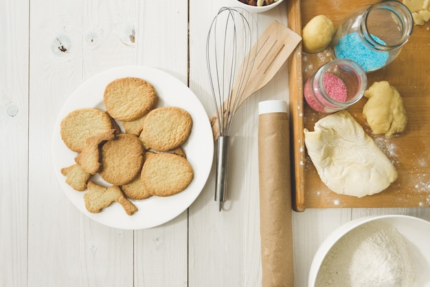 Bekijk van bovenaf op gekookte koekjes op schotel en keukengerei op tafel