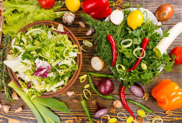 Bekijk van bovenaf van rozemarijn, sla, prei, ui, paprika, citroen en andere heerlijke ingrediënten op houten tafel