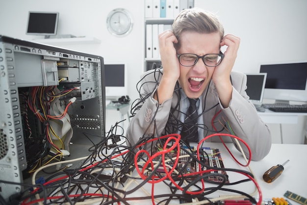 Beklemtoonde computeringenieur die aan gebroken kabels werken