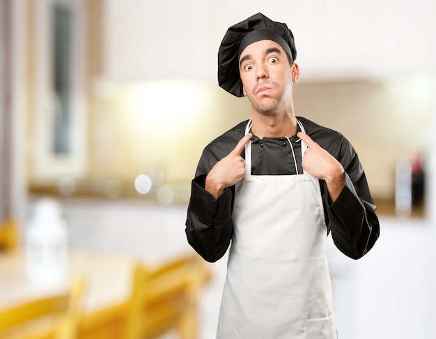 Beklemtoonde jonge chef-kok poseren