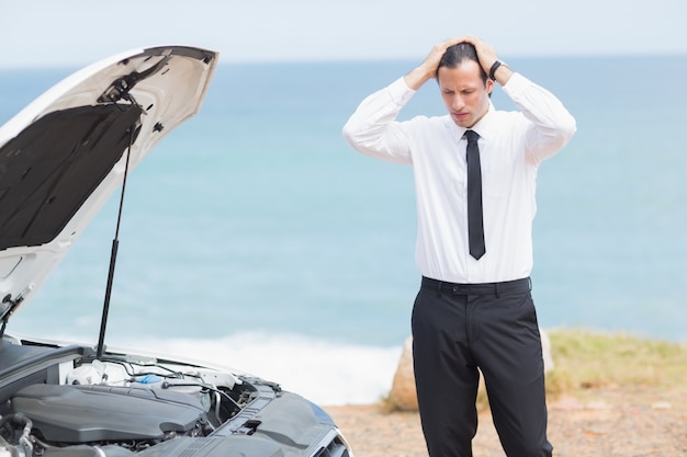 Beklemtoonde zakenman die motor bekijkt