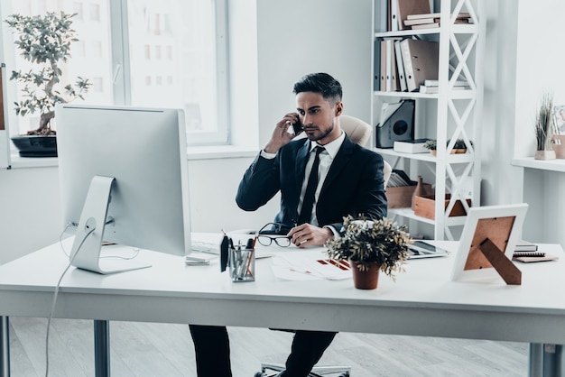 Belangrijk zakelijk gesprek. Ernstige jonge man in formalwear praten aan de telefoon