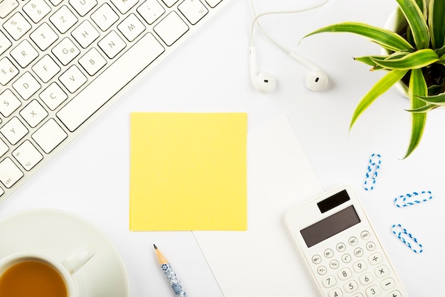 Belangrijke aankondigingen op stukjes papier op bureau met bloem Hoofdtelefoon Pen Calculator Warme drank en toetsenbord Cruciale ideeën op notitie op tafel met potlood en thee