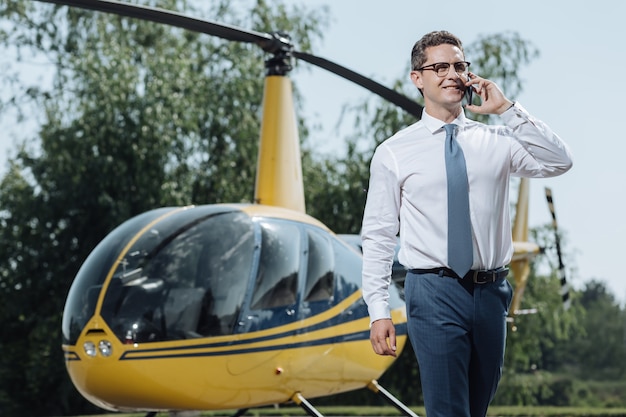 Belangrijke discussie. charmante jonge ceo die details bespreekt met partners aan de telefoon en op het punt staat een vlucht te nemen op een helikopterplatform