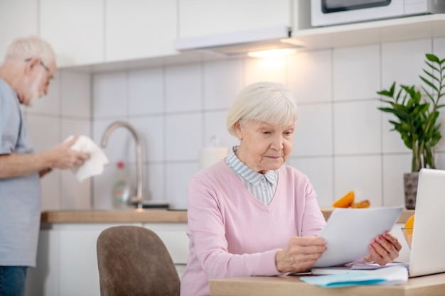 Belangrijke informatie. Grijze haren senior vrouw iets lezen en serieus kijken