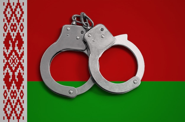 Белорусский флаг и полицейские наручники. Концепция соблюдения закона в стране и защиты от преступности