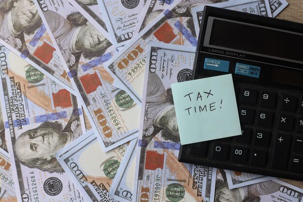 Foto belastingtijd geschreven op een notitie tegen de dollarbiljetten en rekenmachine